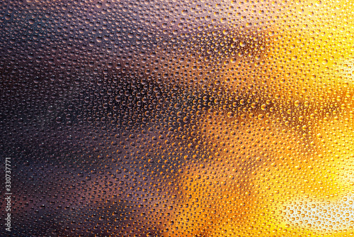 Abstract texture of multiple water drops on glass with bokeh sunset background