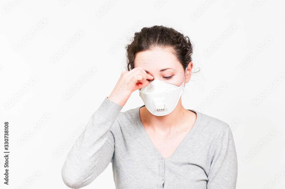 caucasian brunette woman in protective medical mask on face protection for spreading of disease virus SARS-CoV-2, Coronavirus, COVID-19. touching forehead in fever. white background caucasian brunette woman in protective medical mask on face protection for spreading of disease virus SARS-CoV-2, Coronavirus, COVID-19. touching forehead in fever. white background