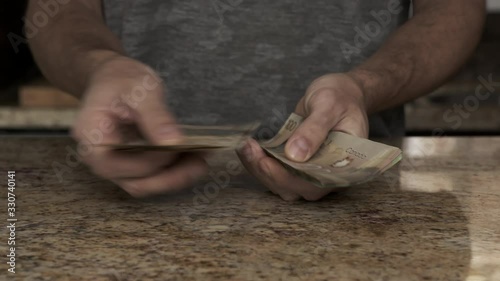 A young man holds money in his hands. A guy counts the Canadian dollars that he took out of the envelope. A young husband recounts a large amount of money. Counting money in a kitchen Payday