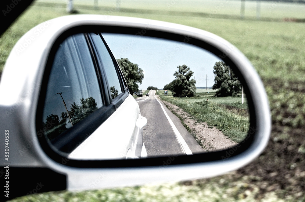 summer road in the reflection of the rear view mirror
