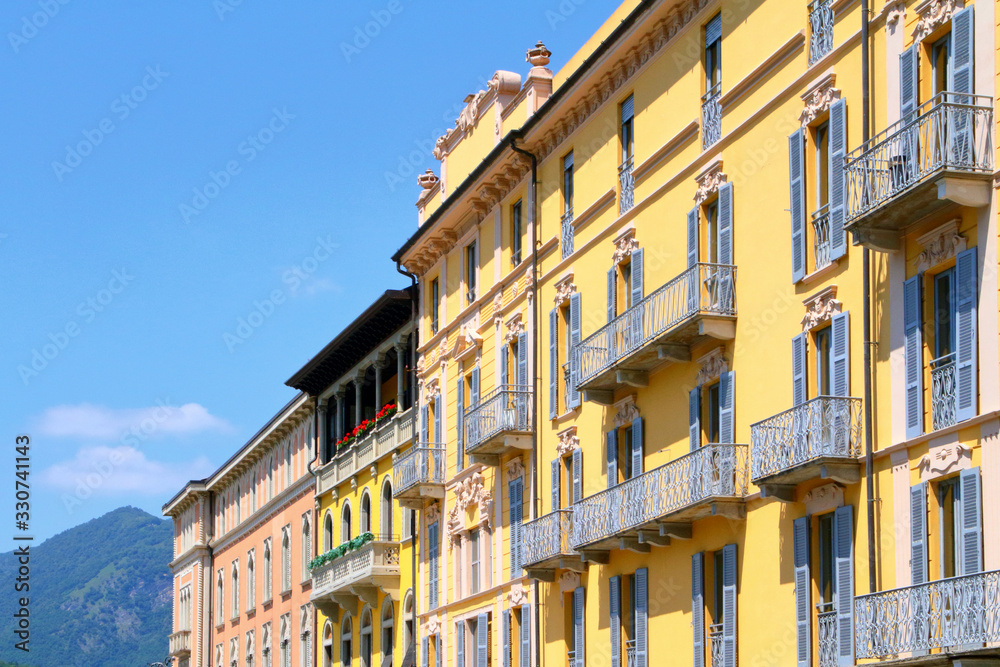 WINDOWS AND BALCONIES OF HISTORICAL COLORED BUILDINGS IN COMO CITY IN ITALY 