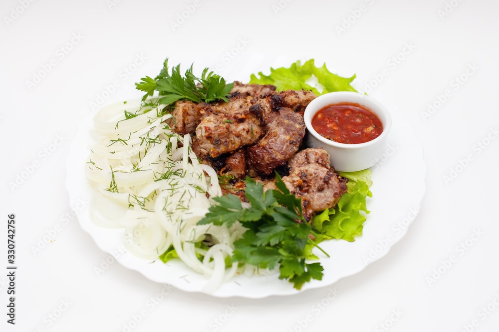 kebab with onions, herbs and sauce on white background