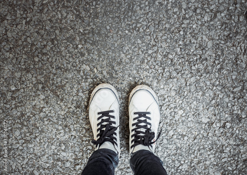 Personal feet selfie with sneakers of traveler standing on street. Travel and wanderlust tourism concept. © sirins