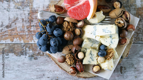 Selective focus. Healthy snack on a wooden tray. Cheese, nuts and fruits. Keto diet. Keto snack.