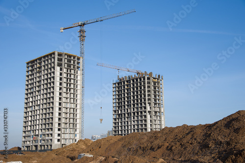 Tower crane lifting a concrete bucket for constructing a new residential build at construction site. Laying or replacement of underground storm sewer pipes. Concrete drainage pipe. © MaxSafaniuk