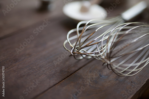 Pastry tools, shallow DOF of wire whisk put on wood table with copy space for bakery background.