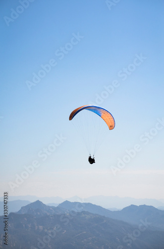 Paracaídas azul y naranja con paracaidista en el cielo deporte extremo
