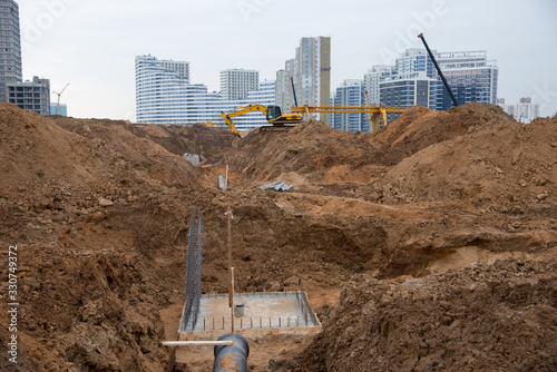 Excavator at construction site during laying sewer and main reticulation systems. Civil infrastructure pipe, water lines, sanitary sewers and storm sewers. Underground utilities installation photo