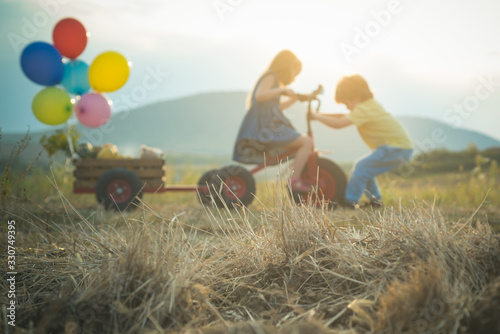 Happy kids with bike on summer field. Cute little farmers - working on spring field. Friendship and support. Summer leisure.