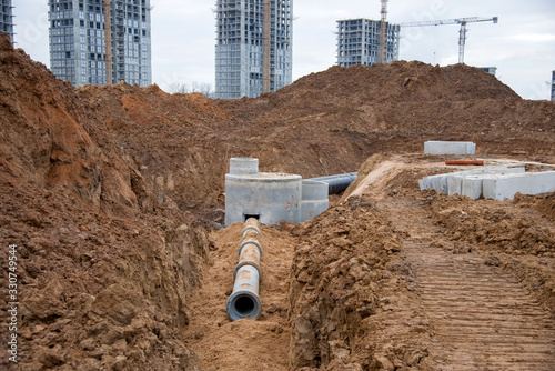 Laying concrete drain pipes and manholes for stormwater system. Connecting a trench drain to a concrete manhole structure at construction site. Construct stormwater and underground utilities,