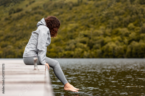 Girl barefooted sitting on a quay in some lake of Scotland