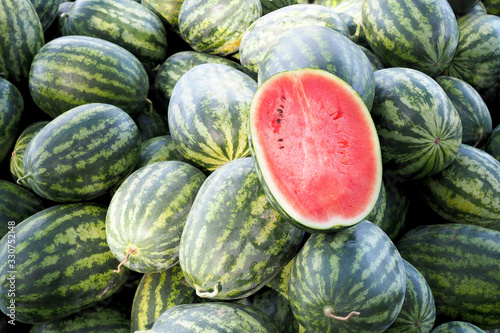 Half watermelon one pice on lot of water melons, Healthy eating. Lots of juicy and ripe watermelons.