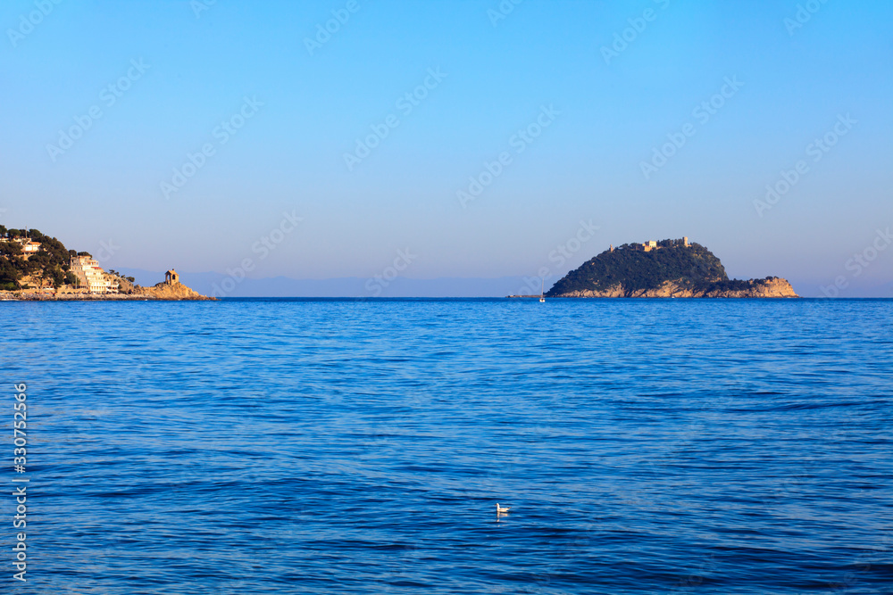 Alassio (SV), Italy - February 15, 2017: The Gallinara island view from Alassio town, Riviera dei Fiori, Savona, Liguria, Italy. Alassio (SV), Italy - February 15, 2017: The Gallinara island view from Alassio town, Riviera dei Fiori, Savona, Liguria, Italy.