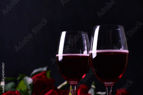 Romantic holiday, glasses with red wine and roses, dark background