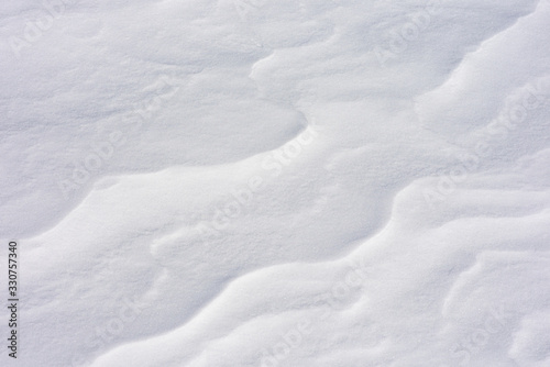 Snow close-up. Wavy texture. The Alpine slope is in the wind