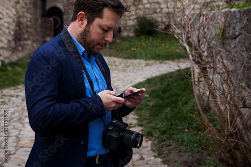Photographer outdoors. Transfering photos from photocamera to smartphone and checking the images