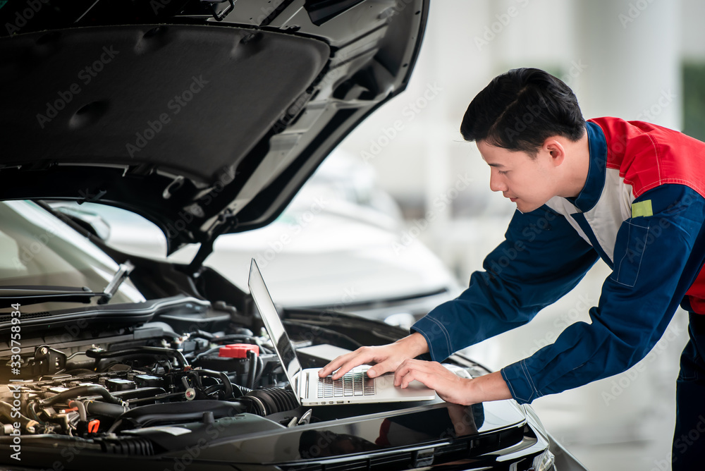 Technicians check and fix cars in the garage The technicians in the auto repair shop use computer systems to check engine problems - car repair services, maintenance concepts. Technicians check and fix cars in the garage The technicians in the auto repair shop use computer systems to check engine problems - car repair services, maintenance concepts.
