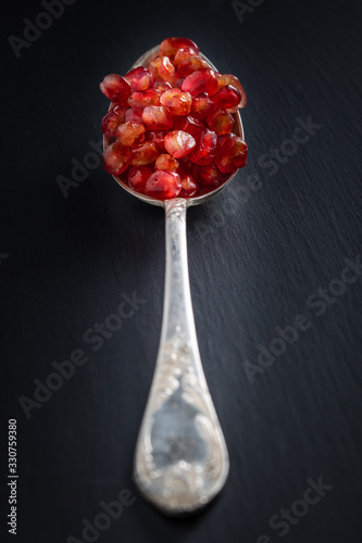 pomegranate and seeds on a plate and silver spoon