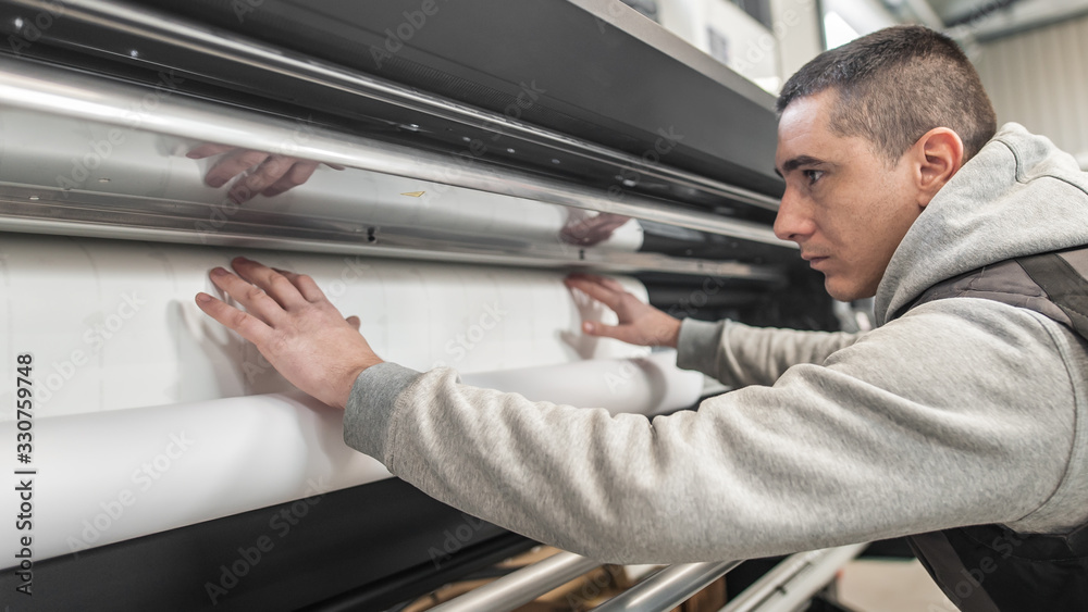 Technician operator changes paper roll on large printer plotter machine Technician operator changes paper roll on large printer plotter machine