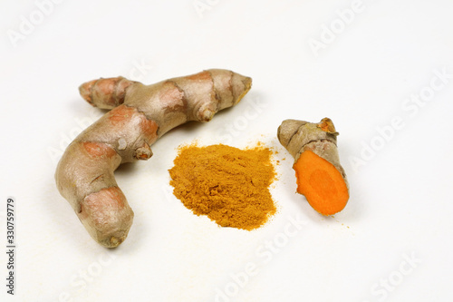 Turmeric powder and fresh turmeric roots isolated on a white background is an ingredient in turmeric foods and ingredients in skin care products. Turmeric helps the skin to be strong