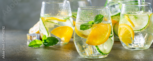 Leinwand Poster Summer healthy lemonade, cocktails of citrus infused water or mojitos, with lime lemon orange, ice and mint, diet detox beverages, in glasses on gray background