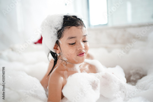 Asian baby kid bathing concept. adorable girl in bathtub with fluffy soap bubble.