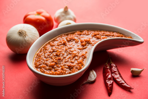 onion tomato masala or puree for indian gravy, served in a bowl with raw tamatar, pays and lehsun and red chilli, selective focus photo