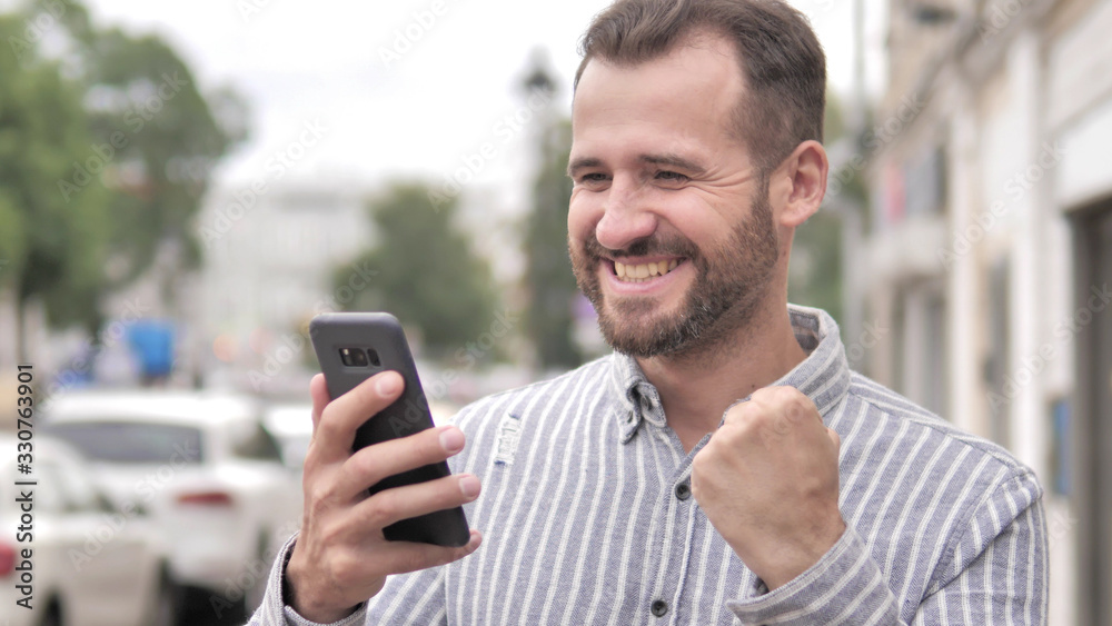 Outdoor Beard Casual Man Excited for Success on Smartphone Outdoor Beard Casual Man Excited for Success on Smartphone