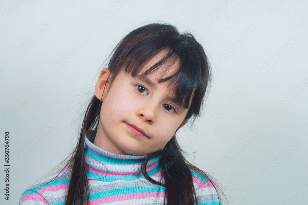 Portrait of a cheerful child with long hair and a striped sweater. girl fooling around Portrait of a cheerful child with long hair and a striped sweater. girl fooling around