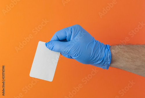 hand in a blue medical glove holds a blank form of paper on a yellow background. Mock up, business card
