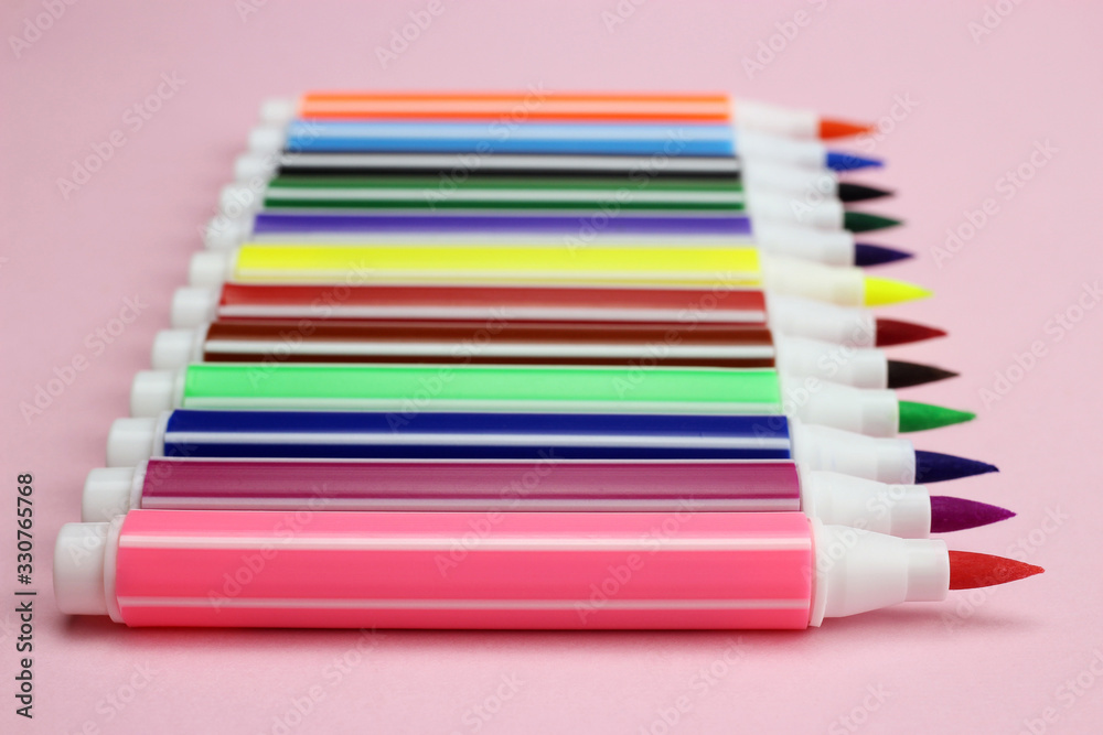 Fototapeta premium colored markers in a row on a pink background