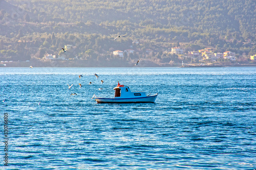 Fishing boat in the middle of the sea, seagulls flying above the boat