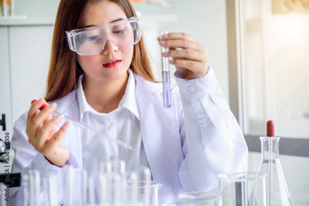 Attractive scientist woman lab technician assistant analyzing sample in test tube at laboratory. Medical, pharmaceutical and scientific research and development concept.