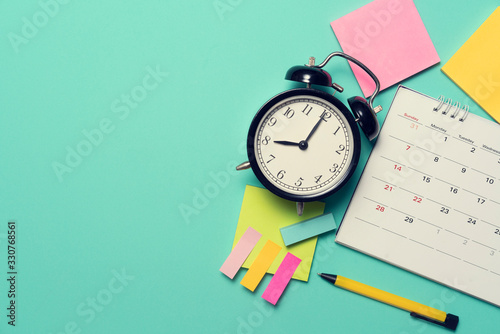 close up of calendar and alarm clock on the green table background, planning for business meeting or travel planning concept photo