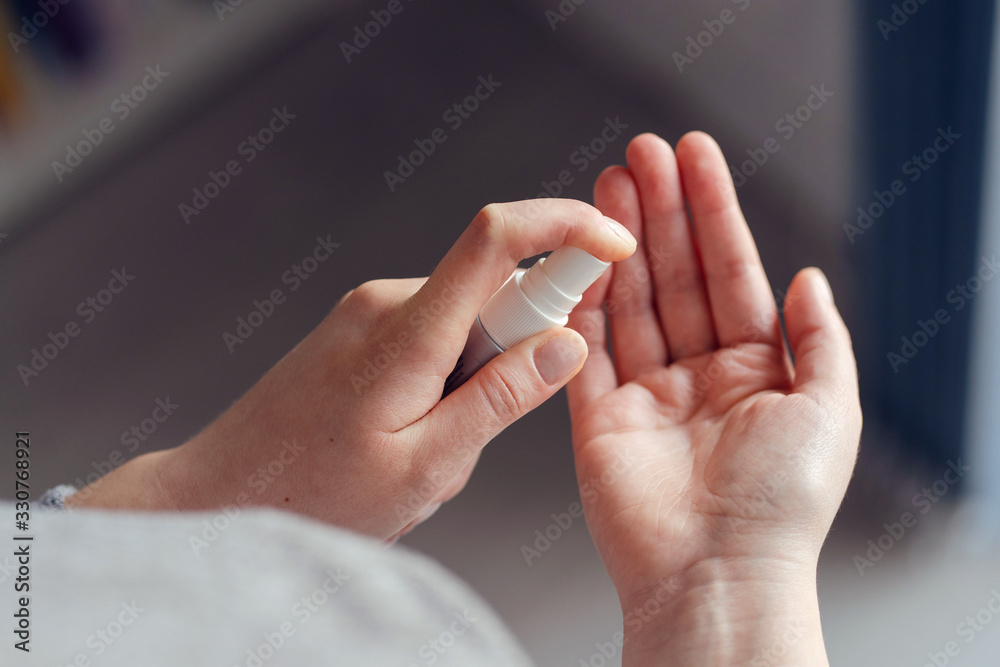 High angle view on unknown female person caucasian woman or girl applying spray disinfection alcohol product on hand disinfecting hands against virus bacteria health prevention in day at home or work High angle view on unknown female person caucasian woman or girl applying spray disinfection alcohol product on hand disinfecting hands against virus bacteria health prevention in day at home or work
