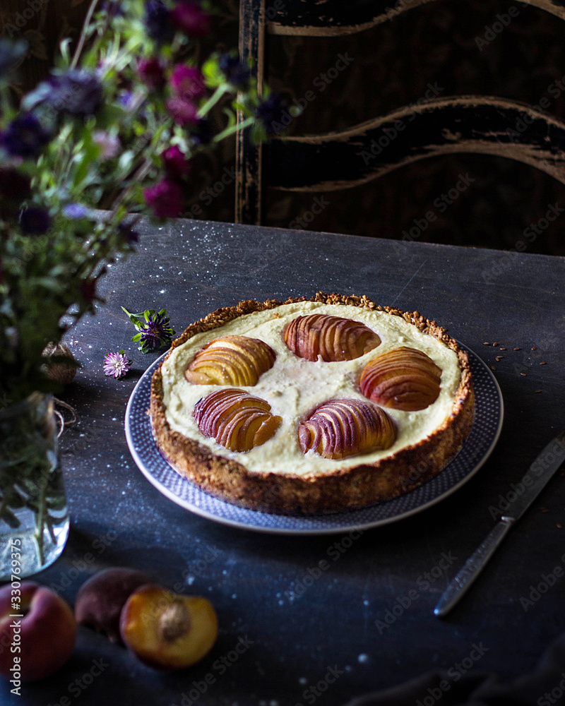 Cheesecake with peaches on a dark table with a bouquet of flowers. Cheesecake with peaches on a dark table with a bouquet of flowers.