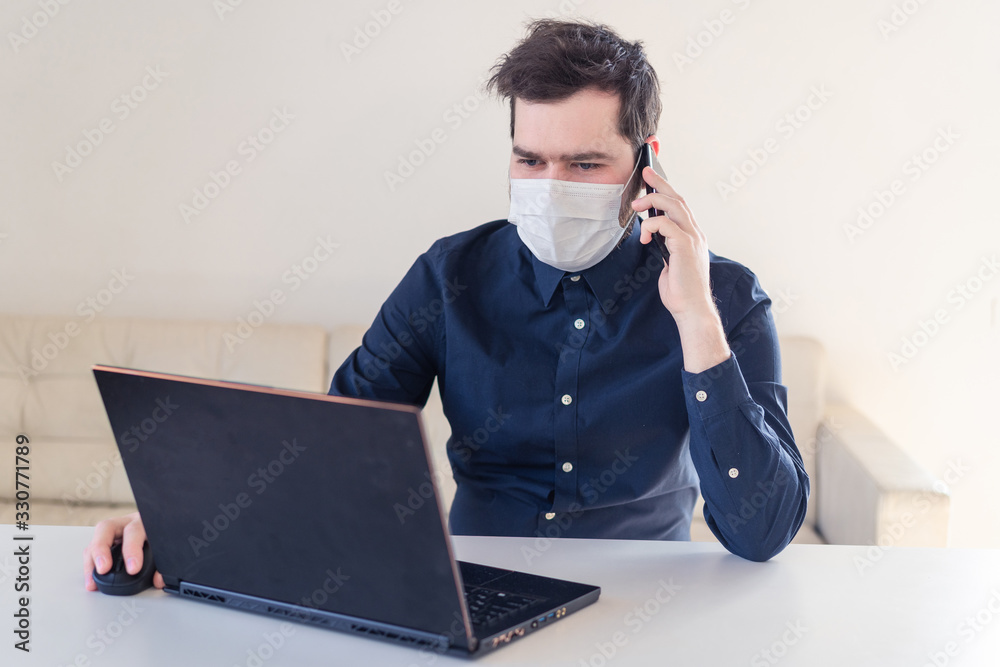Men remote work from home behind laptop during epidemic in medical mask