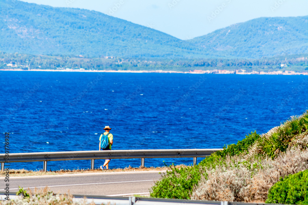 Naklejka premium Hiker walking by the sea on a sunny springtime day