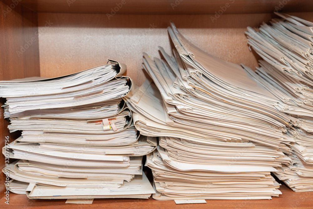 Old paper documents stacked in archive. Documents on the shelves of archive room. Office shelves in the closet full of files