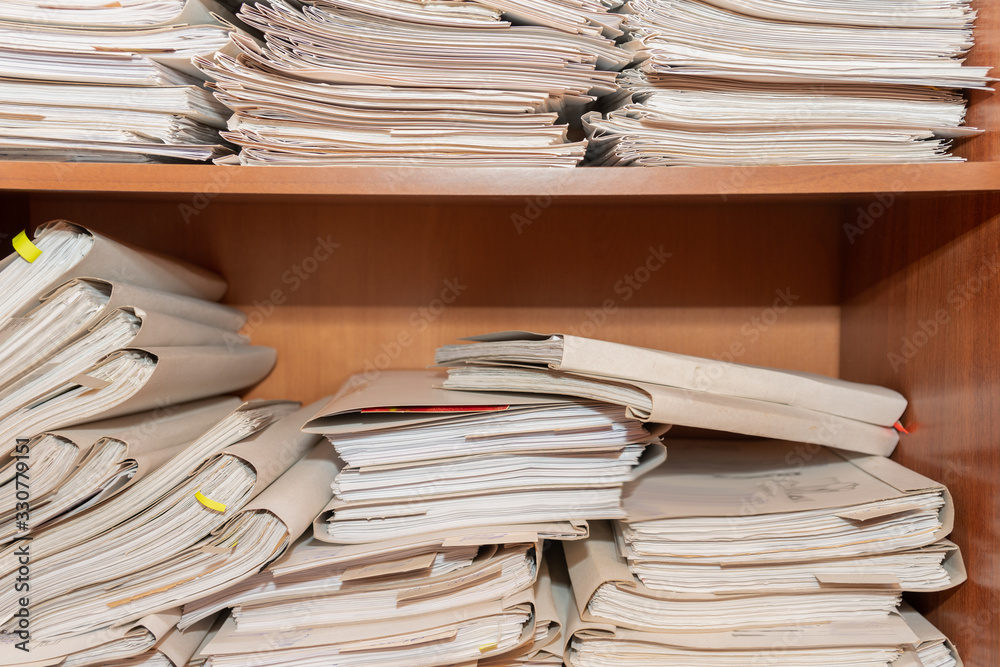 Old paper documents stacked in archive. Documents on the shelves of archive room. Office shelves in the closet full of files Old paper documents stacked in archive. Documents on the shelves of archive room. Office shelves in the closet full of files
