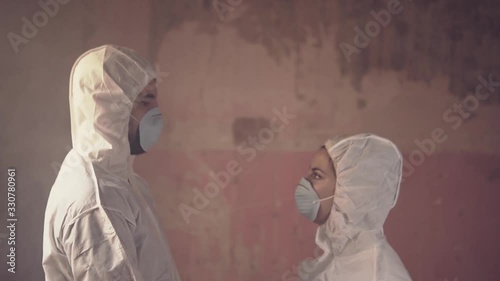 Slow motion video of two doctor scientists wearing bio hazard suit and gear to avoid contamination looking at each other during a corona virus pandemic photo