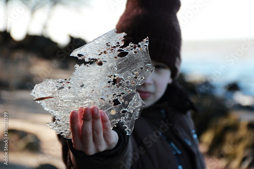 the boy holds in his hands a piece of ice in which grains of sand froze