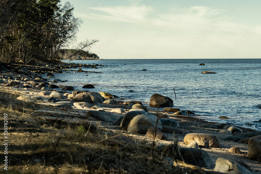 sunny beach with blue water and large rocks in the sand sunny beach with blue water and large rocks in the sand
