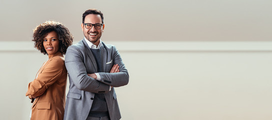 Portrait of happy multi ethnic business couple posing with arms crossed