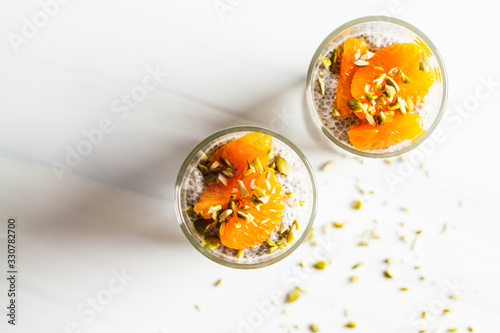 Chia pudding with tangerine and pumpkin seeds in glass, top view. Healthy vegan food concept.