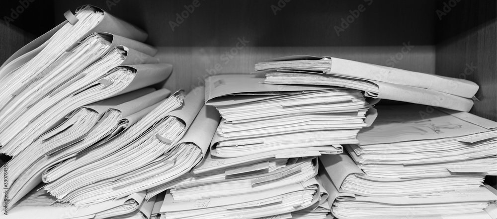 Paper documents stacked in archive. Documents on the shelves of archive room. Office shelves in the closet full of files. black and white photo Paper documents stacked in archive. Documents on the shelves of archive room. Office shelves in the closet full of files. black and white photo