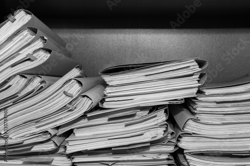 Paper documents stacked in archive. Documents on the shelves of archive room. Office shelves in the closet full of files. black and white photo