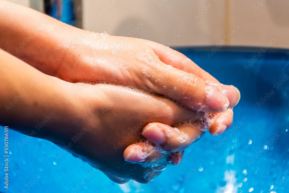 Naklejka premium A slow motion close-up shot of a young woman washing her hands with soap thoroughly