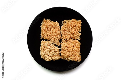 Top eye view closeups of ready for serving to cook dry broken instant noodles a half in the black plate isolated on a white background, separate pieces