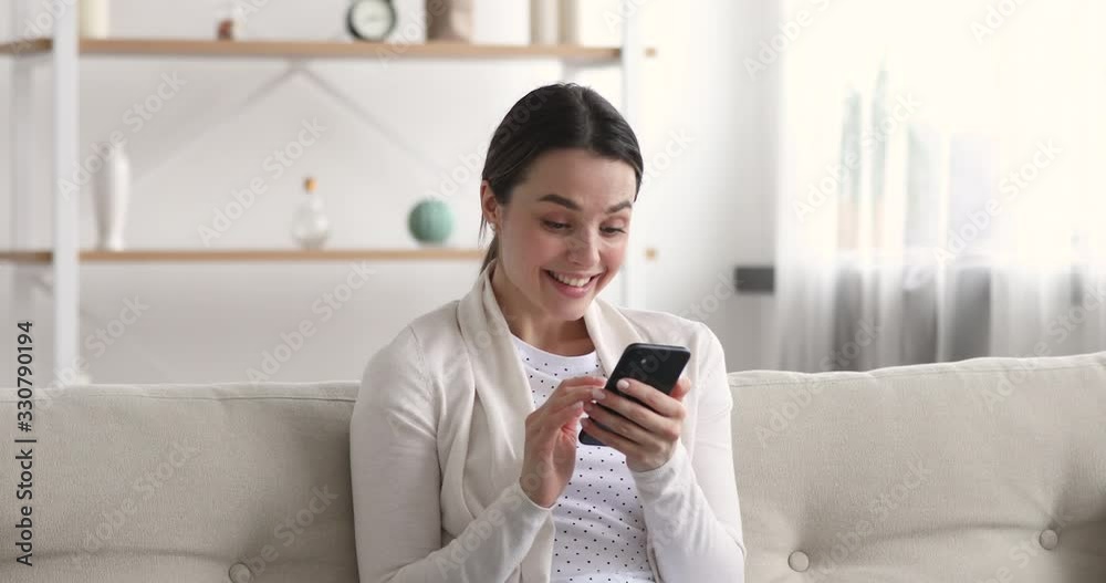 Funny euphoric young woman customer celebrating winning bid or getting ecommerce shopping offer on smartphone. Excited girl winner looking at mobile phone using app celebrating success concept.